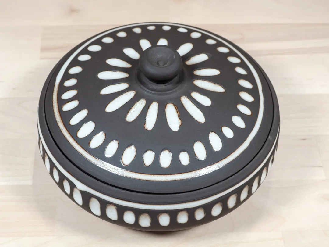 Wide and shallow lidded jar from black stoneware and white fluted texture